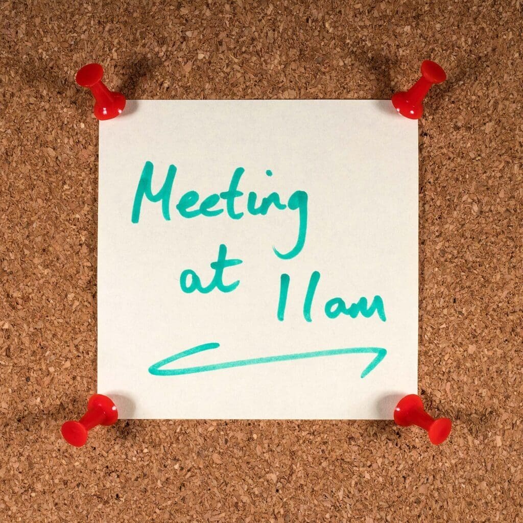 Close-up of a Meeting at 11am reminder message, pinned to a noticeboard.